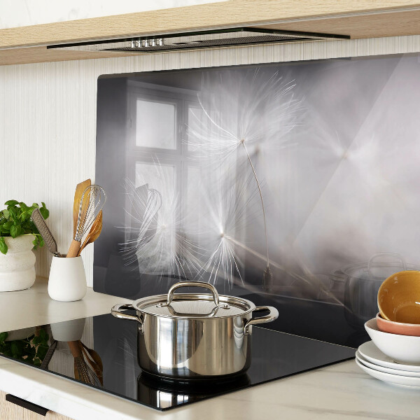 Glazen snijplanken Pluizige paardenbloemen tegen de achtergrond van het raam.