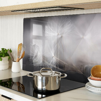 Glazen snijplanken Pluizige paardenbloemen tegen de achtergrond van het raam.