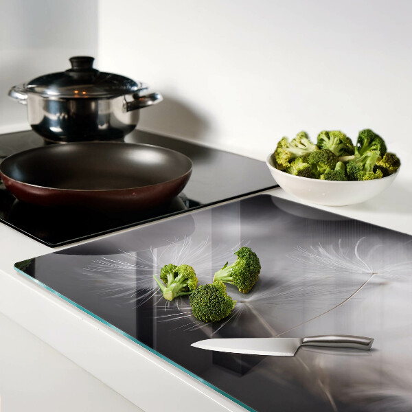 Glazen snijplanken Pluizige paardenbloemen tegen de achtergrond van het raam.