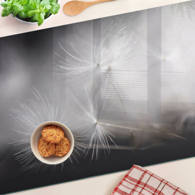 Glazen snijplanken Pluizige paardenbloemen tegen de achtergrond van het raam.