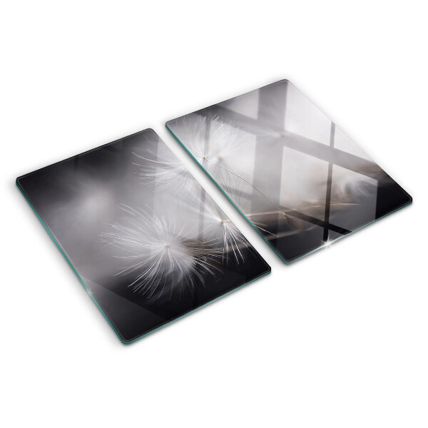 Glazen snijplanken Pluizige paardenbloemen tegen de achtergrond van het raam.