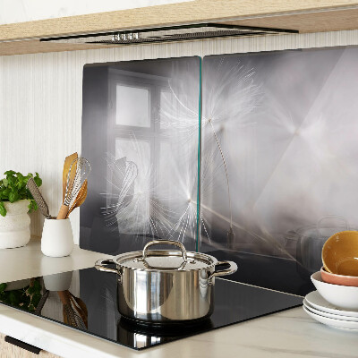 Glazen snijplanken Pluizige paardenbloemen tegen de achtergrond van het raam.