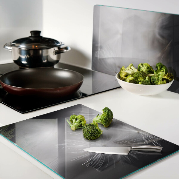 Glazen snijplanken Pluizige paardenbloemen tegen de achtergrond van het raam.