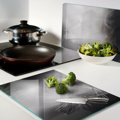 Glazen snijplanken Pluizige paardenbloemen tegen de achtergrond van het raam.