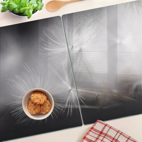 Glazen snijplanken Pluizige paardenbloemen tegen de achtergrond van het raam.