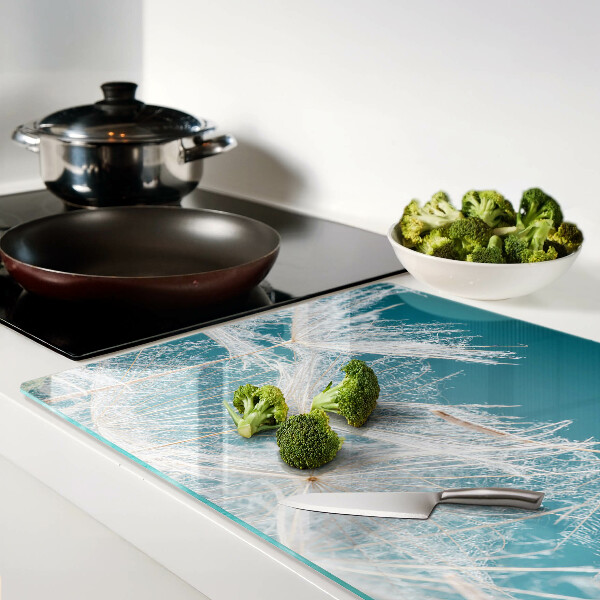 Snijplanken van glas Paardenbloemen op een blauwe achtergrond