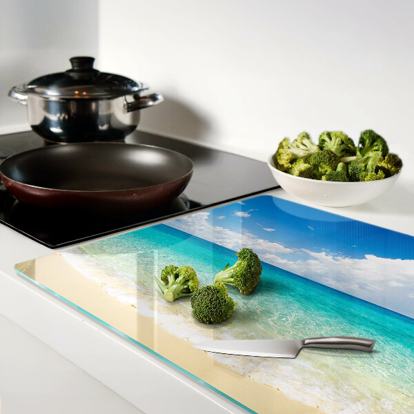 Snijplanken van glas Een strand met turquoise water en wolken.