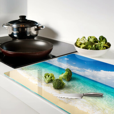 Snijplanken van glas Een strand met turquoise water en wolken.