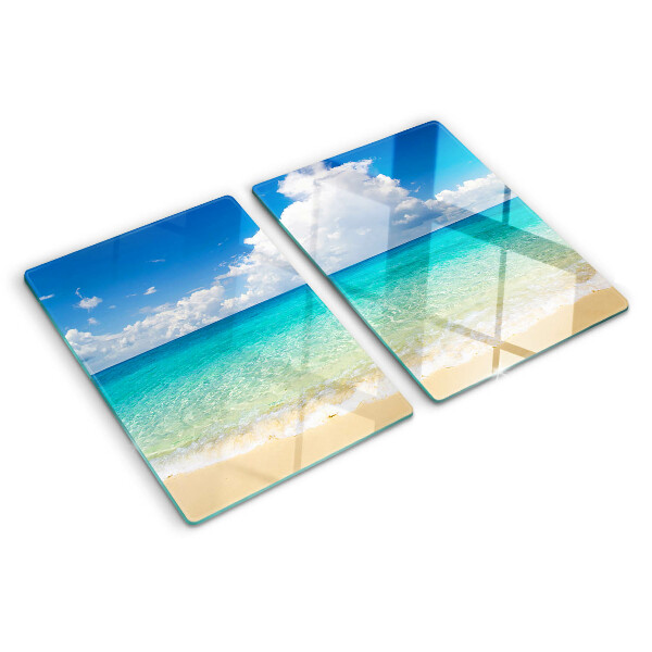 Snijplanken van glas Een strand met turquoise water en wolken.