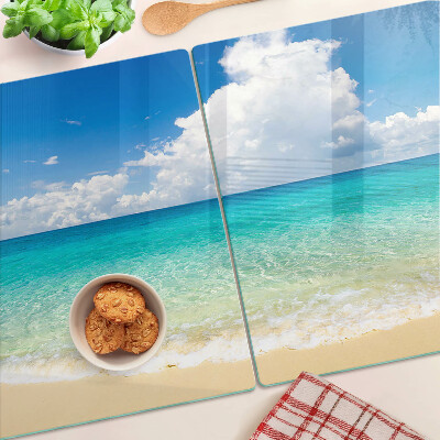 Snijplanken van glas Een strand met turquoise water en wolken.