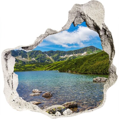 3D muursticker effect gat in de muur Een bergmeer omgeven door groen.