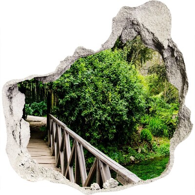3D muursticker effect gat in de muur Een groen paradijs met een houten brug.