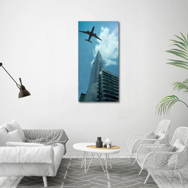 Verticaal schilderij op canvas Een vliegtuig boven de stad