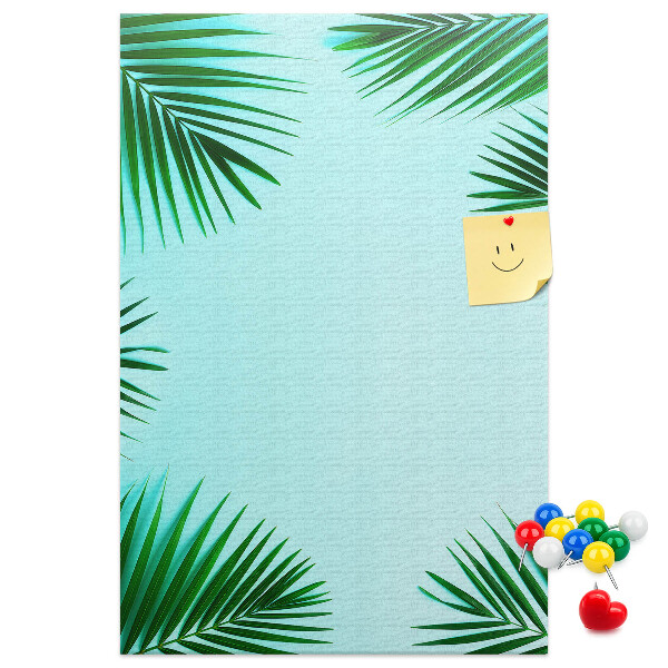 Memobord van kurk met palmbladeren op een blauwe achtergrond