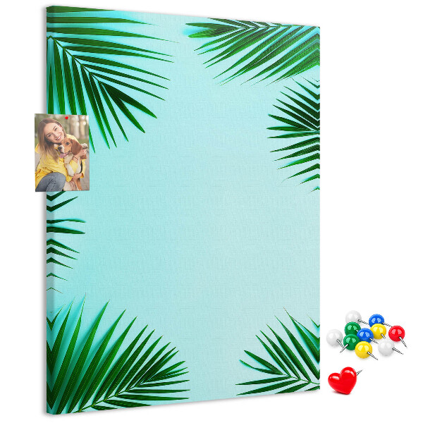Memobord van kurk met palmbladeren op een blauwe achtergrond