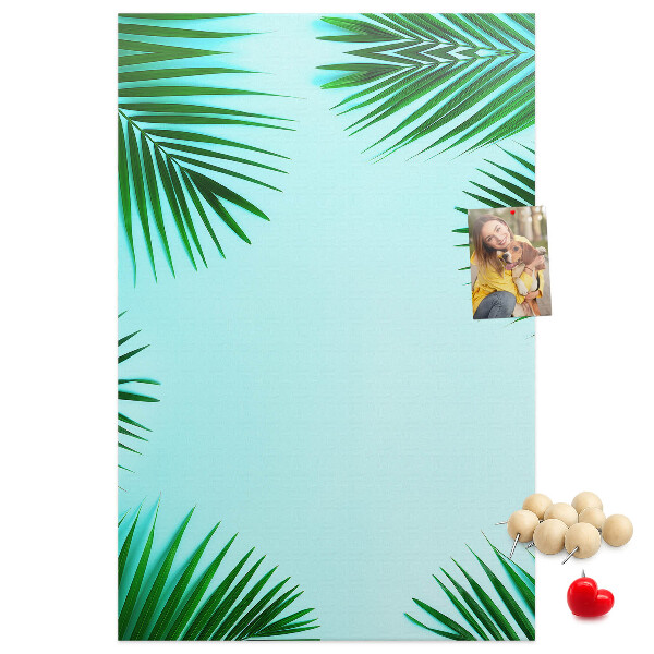 Memobord van kurk met palmbladeren op een blauwe achtergrond