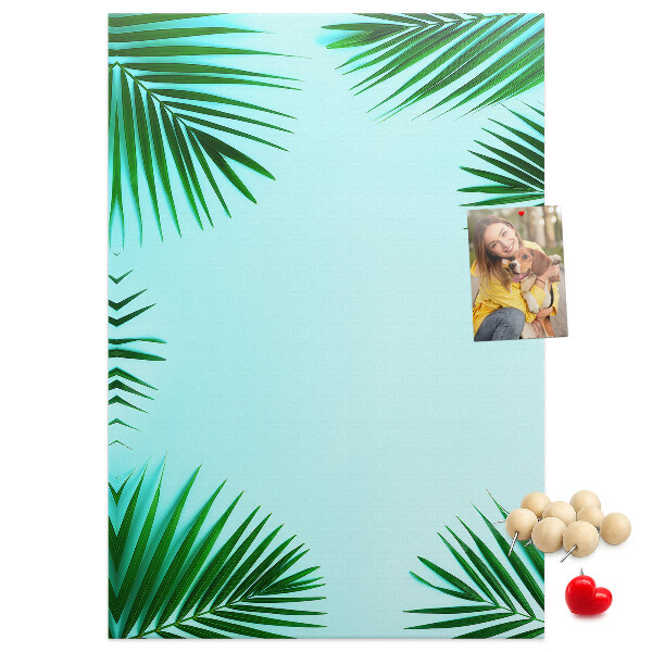 Memobord van kurk met palmbladeren op een blauwe achtergrond