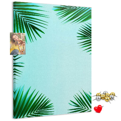 Memobord van kurk met palmbladeren op een blauwe achtergrond
