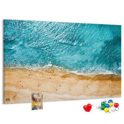Kurkbord met een afbeelding van een strand met golven en voetsporen