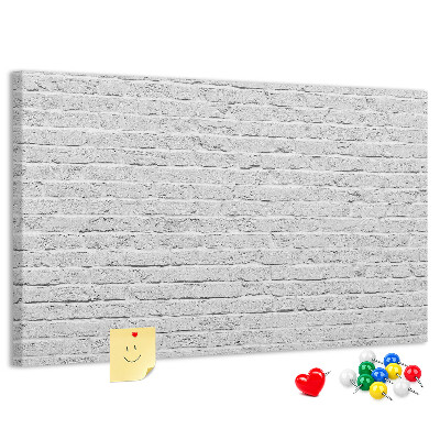 Kurk prikbord met afbeelding van witte bakstenen muur met kleurrijke punaises