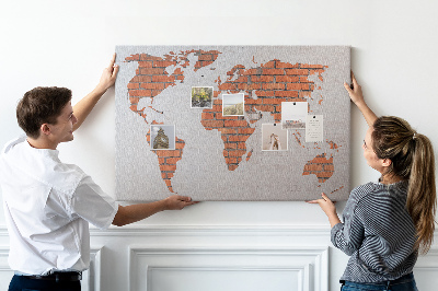 Kurkbord wereldkaart tegen een bakstenen muur